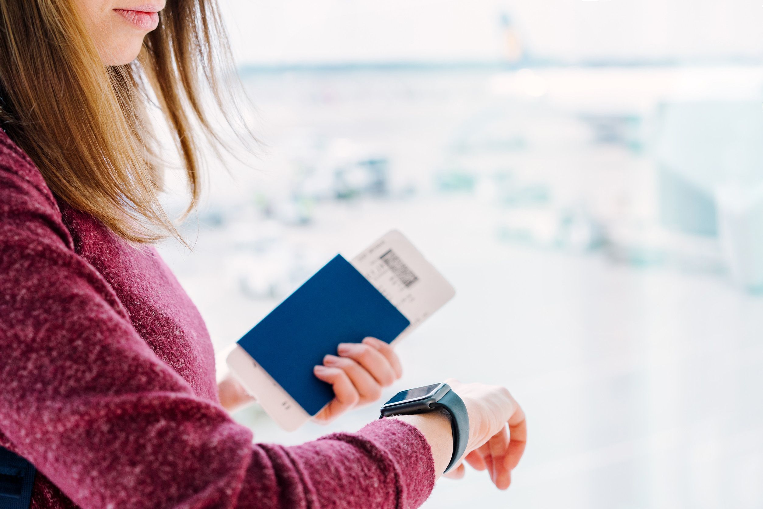 Female Passenger Standing Near The Window With Her Passport And Boarding Pass