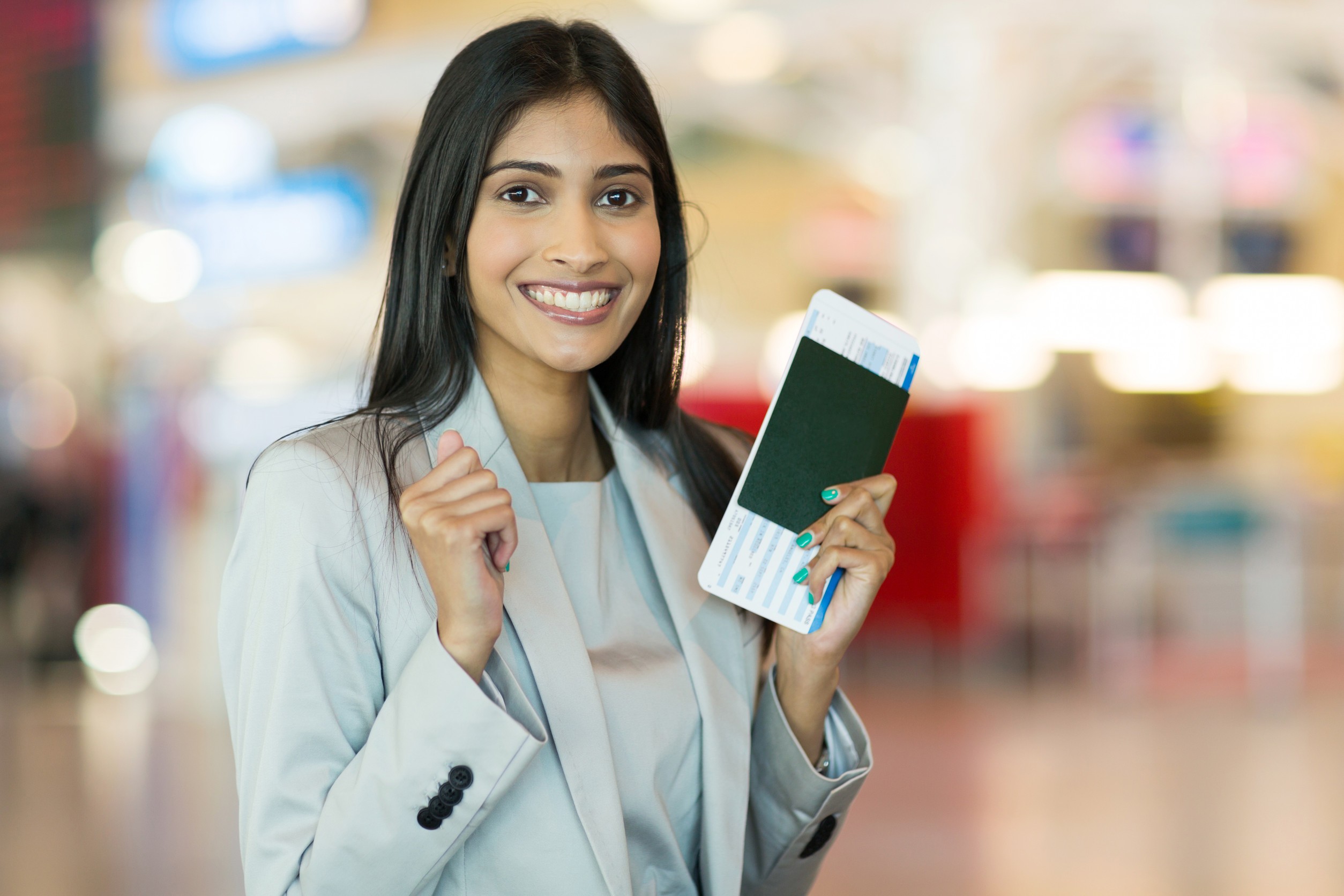 Indian woman holding a passport and boarding pass at the airport